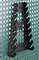 A black, serrated tool holder is vertically mounted on a green, perforated wall.