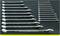 A row of 18 polished spanners in various sizes, neatly arranged side by side on a dark surface.
