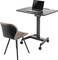 Desk with an adjustable height tabletop and a laptop placed on it; beside it, an upholstered chair with black legs.