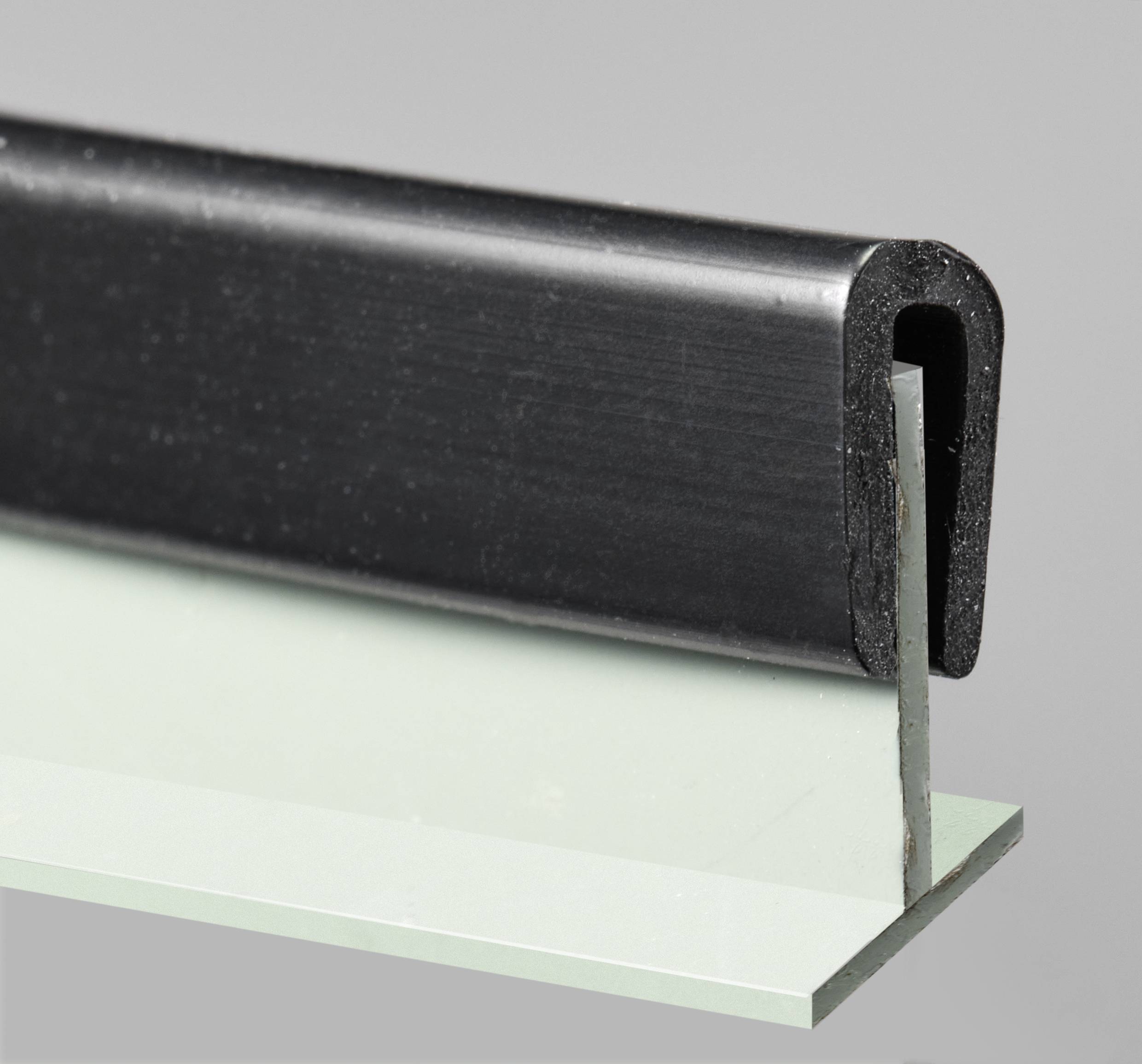 Black rubber profile mounted on the edge of a green surface, demonstrating use for edge protection.