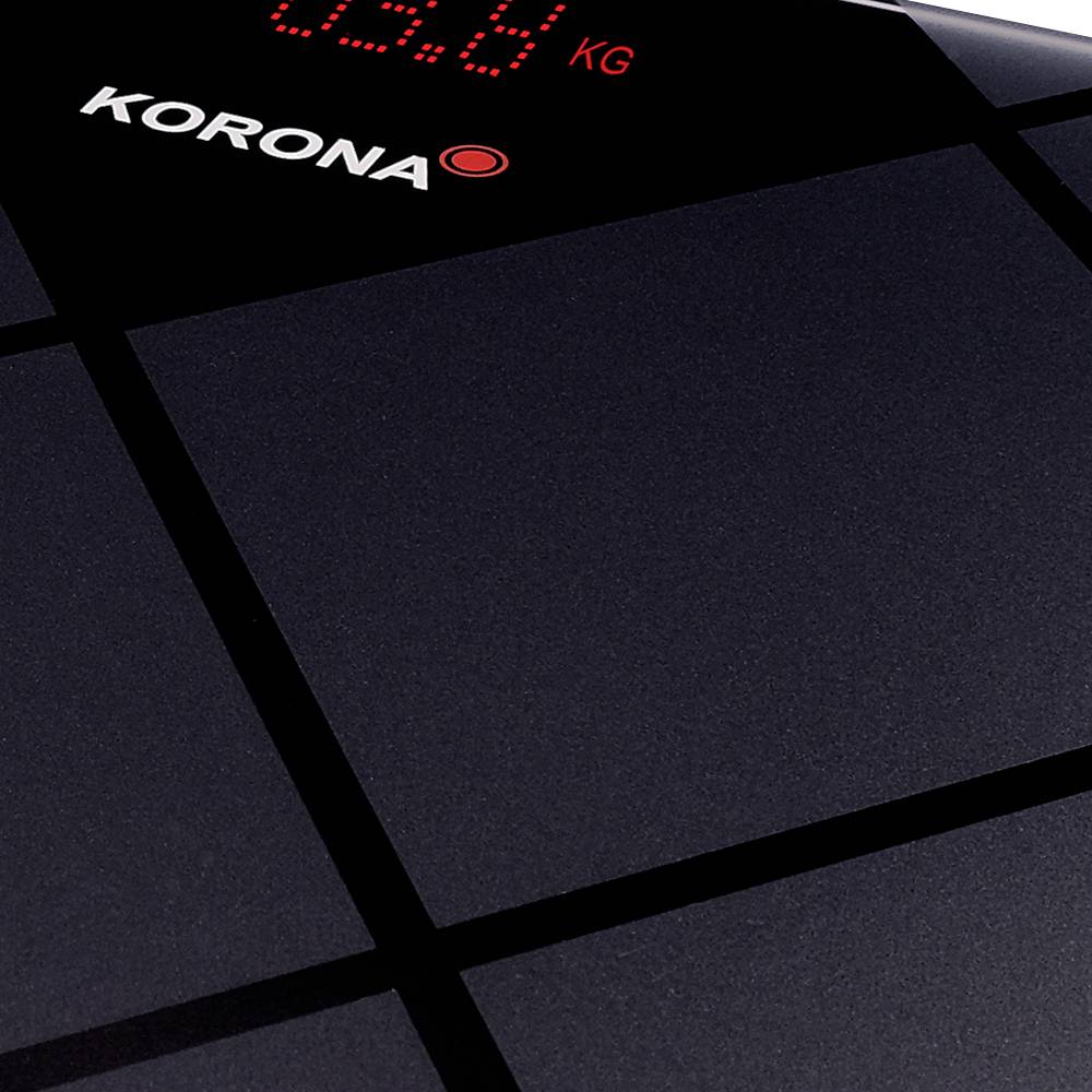 Digital bathroom scales with a red illuminated display reading '0.0 KG' and the 'Korona' brand, placed on a smooth black surface.