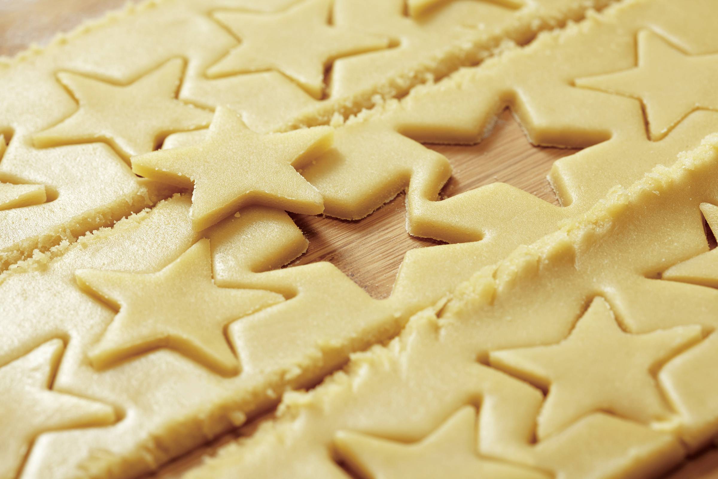 Star-shaped biscuits are cut out from the dough. Dough on a wooden board.