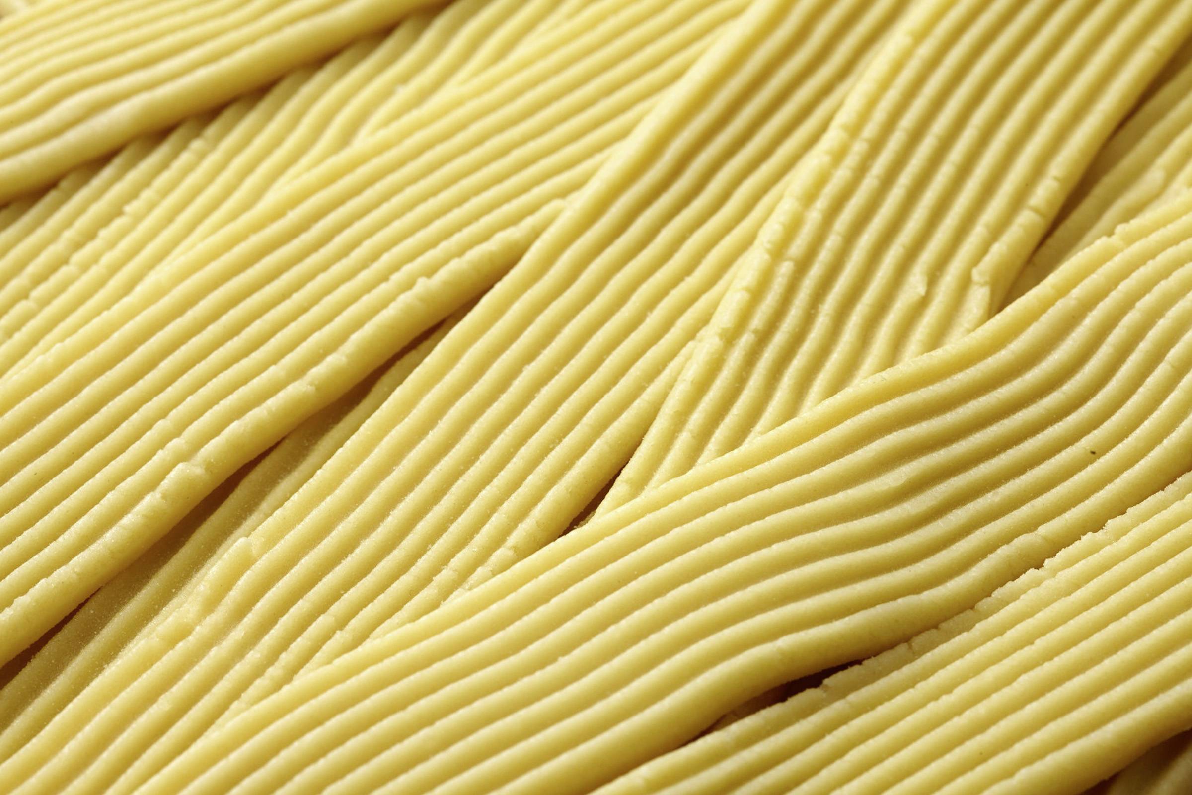 Close-up of folded, yellow, crinkled strips that look like dough or ribbon.