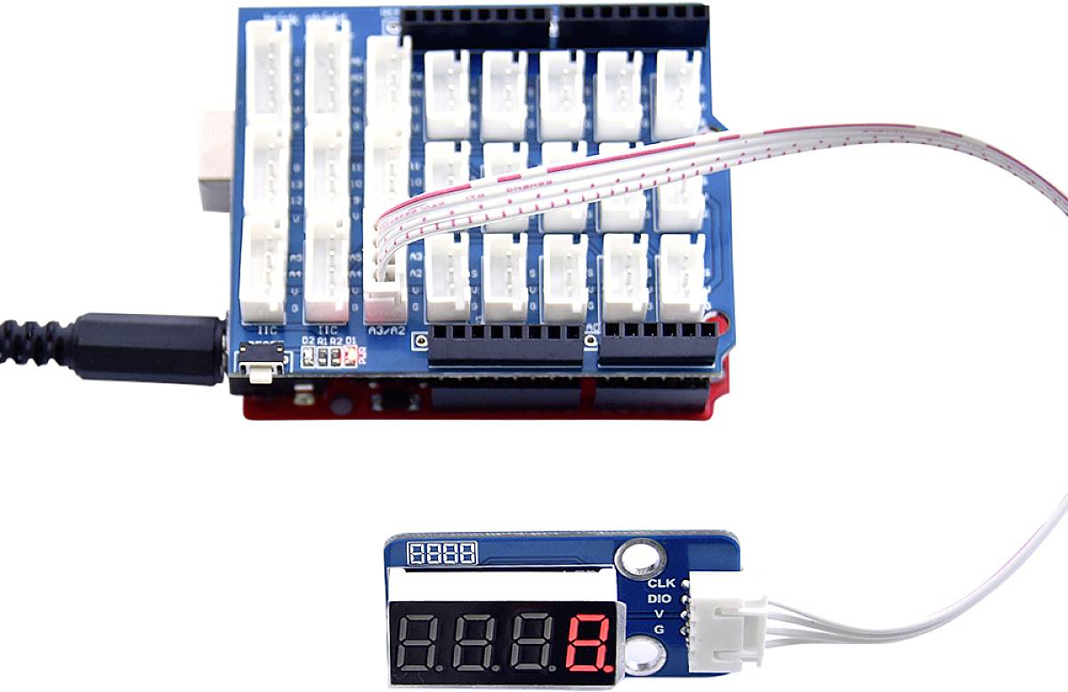 A microcontroller board with multiple ports is connected to a digital display showing the number '8'.