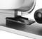 Silver food slicer with a blade and a carriage, used for slicing food items.
