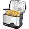 A stainless steel deep fat fryer with an open lid, filled with golden brown potato croquettes in a metal basket.