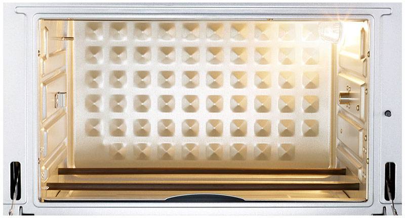 An empty, open oven with an illuminated interior and a diamond-shaped pattern on the walls.