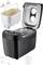Black bread maker with open lid, removable baking pan, display and accessories such as measuring cup and hook.