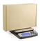 A digital scale displays 7.9 kg while weighing a large, sealed, brown cardboard box.