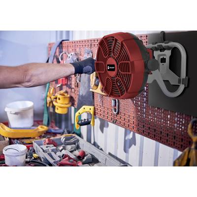 A person is hanging a red extension pipe on a wall mounting in a workshop. Tools are visible in the foreground.