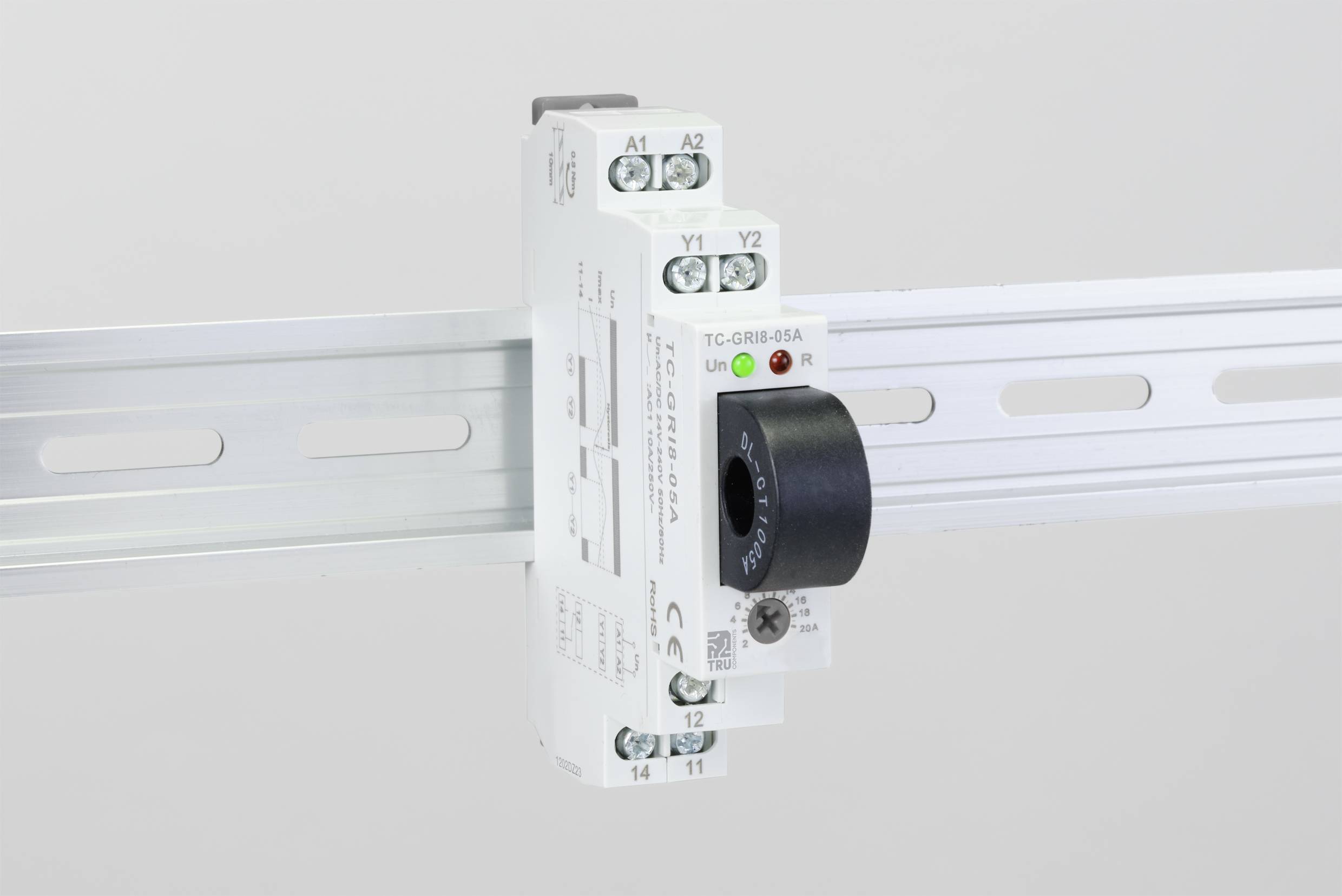 An electrical device is mounted on a DIN rail. It has connections, switches, and an LED indicator.