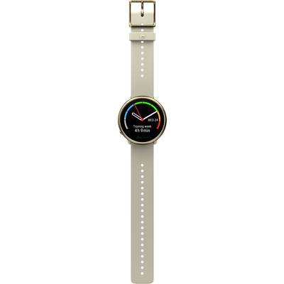 A smartwatch with a round display shows the date and time, has fitness indicators and a beige strap.