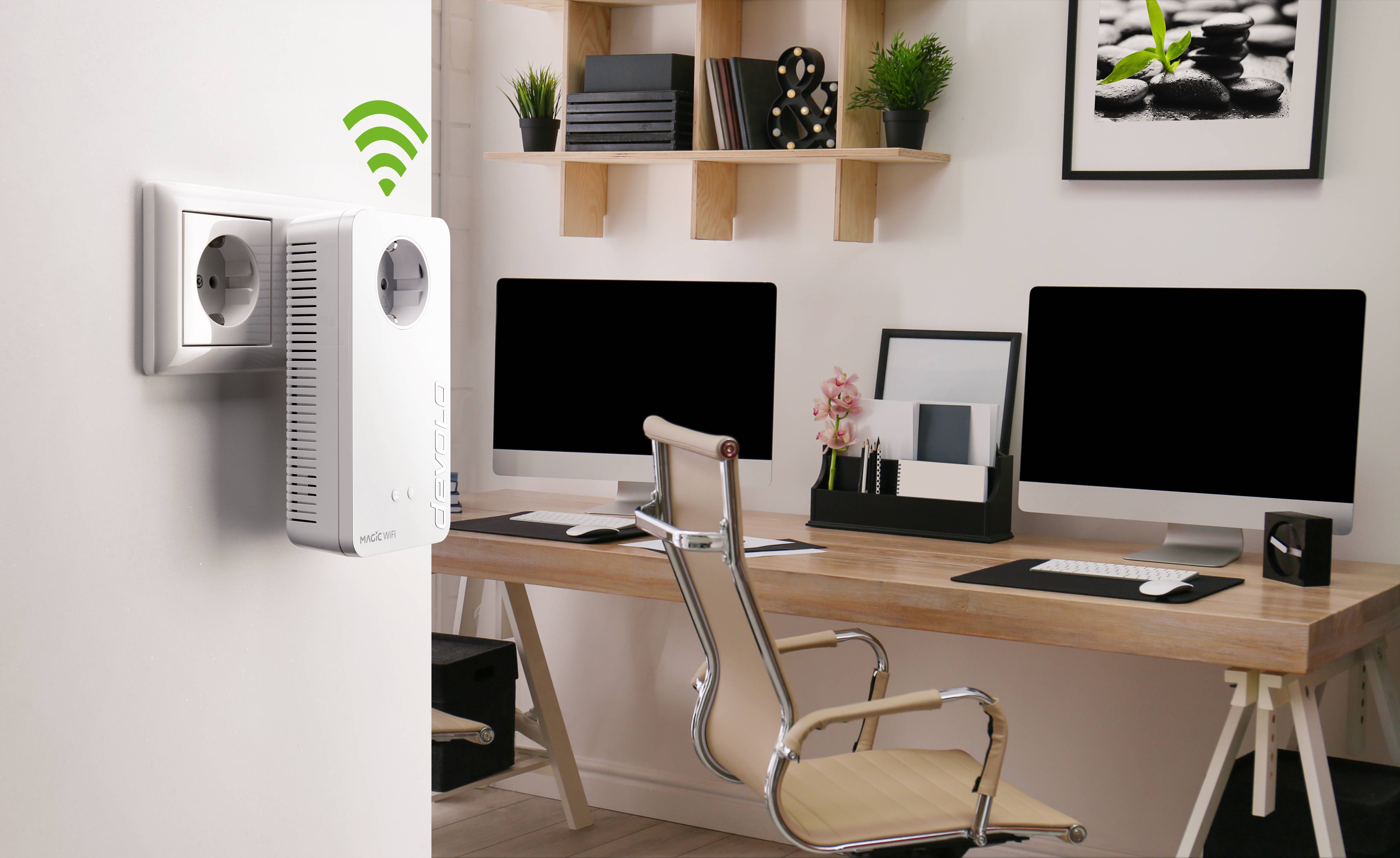 A home office space with a wooden desk, two computer monitors and a Wi-Fi adapter plugged into the wall socket.