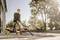 A person is cleaning a patio with an industrial vacuum cleaner on a sunny day. Trees are visible in the background.