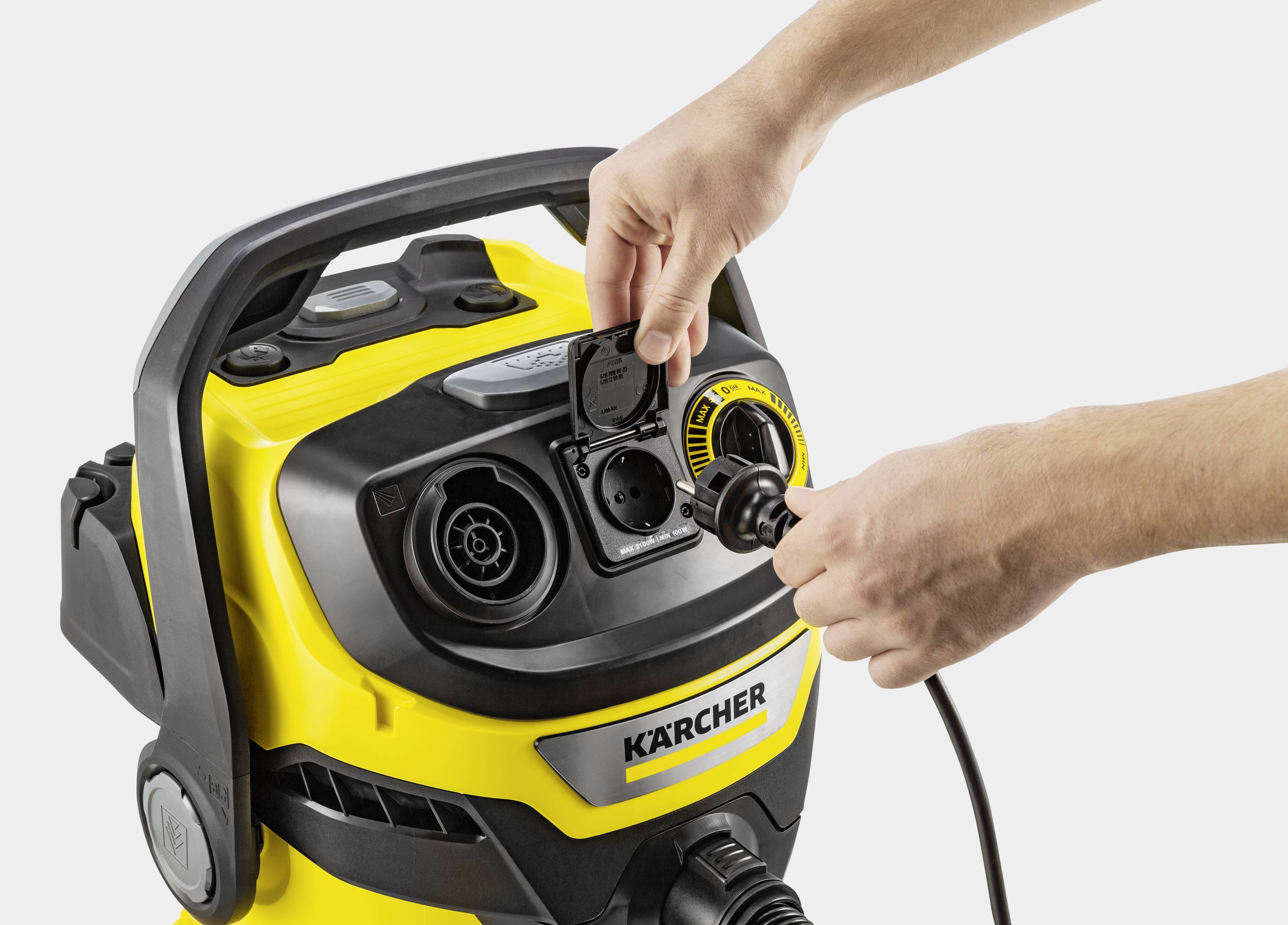 A yellow cleaning machine by Kärcher is being operated by a person, with a plug being inserted.