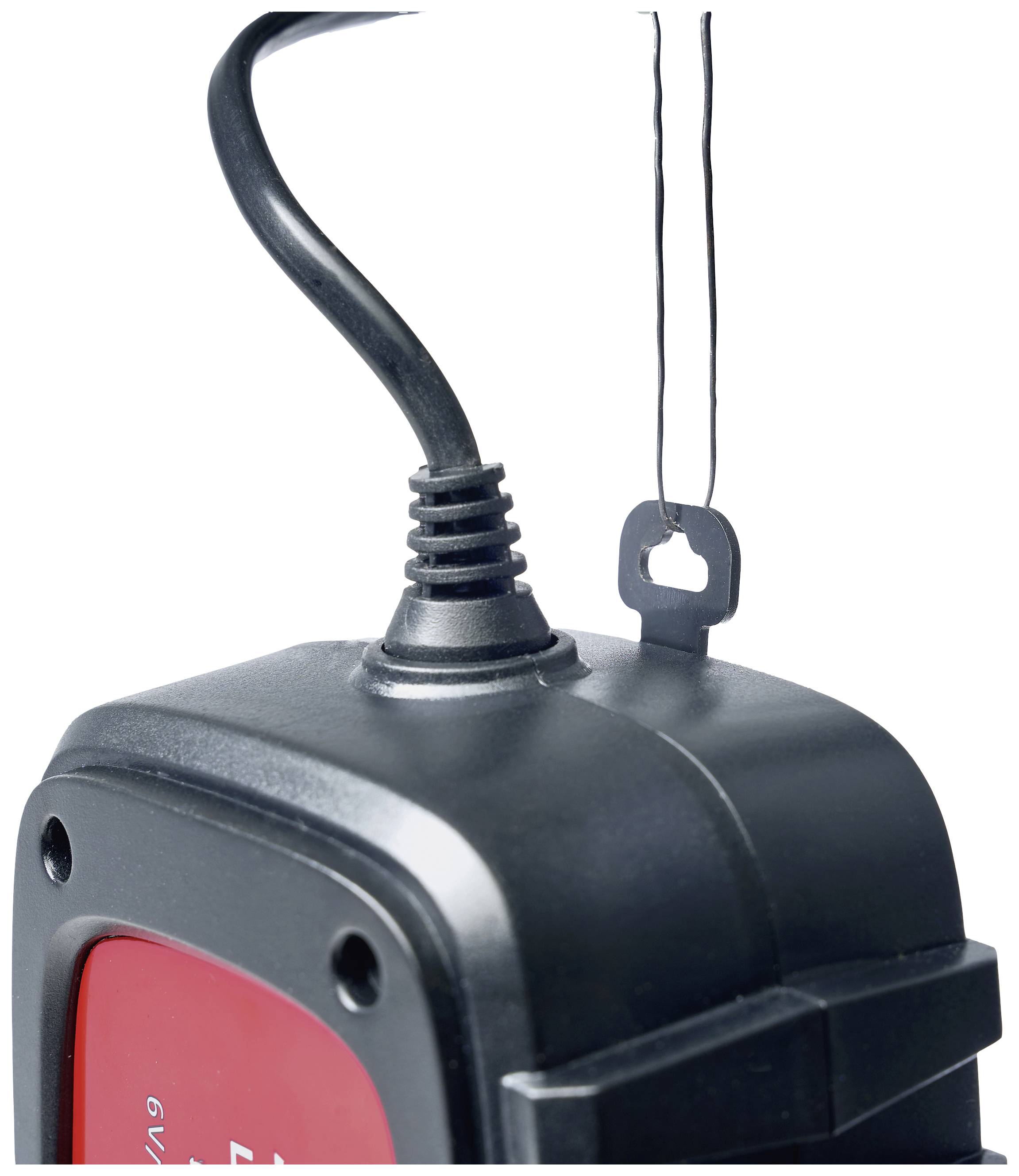 Black electric device with a red label and cable hanging on a hook.