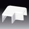 A white, L-shaped plastic cover in front of a dark background. It is likely used to protect cables or corners.