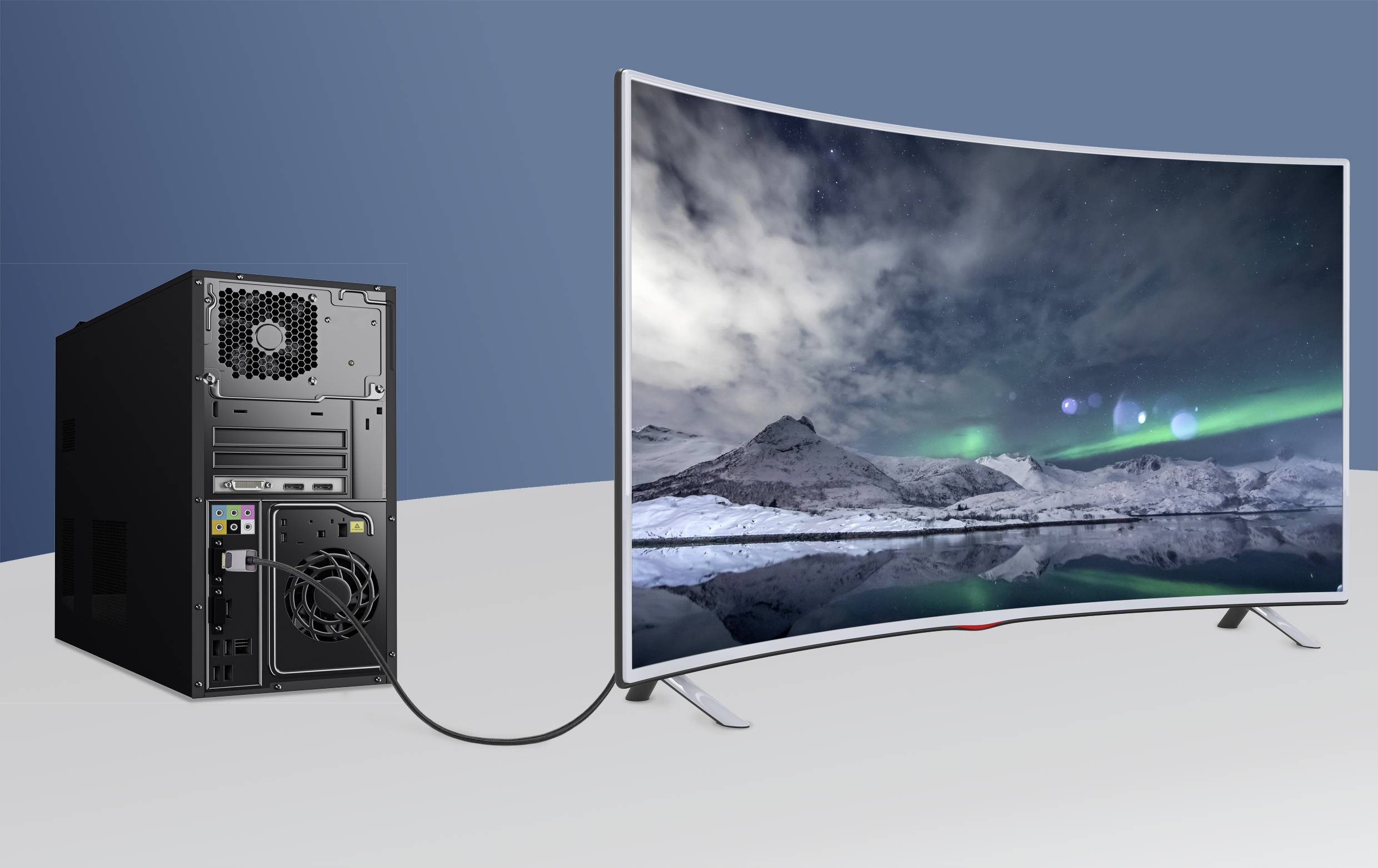 'A desktop computer is connected to a curved monitor displaying an image of snow-covered mountains beneath the night sky.'