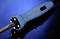 A soldering iron with a blue handle lies on a reflective surface in front of a blue background.