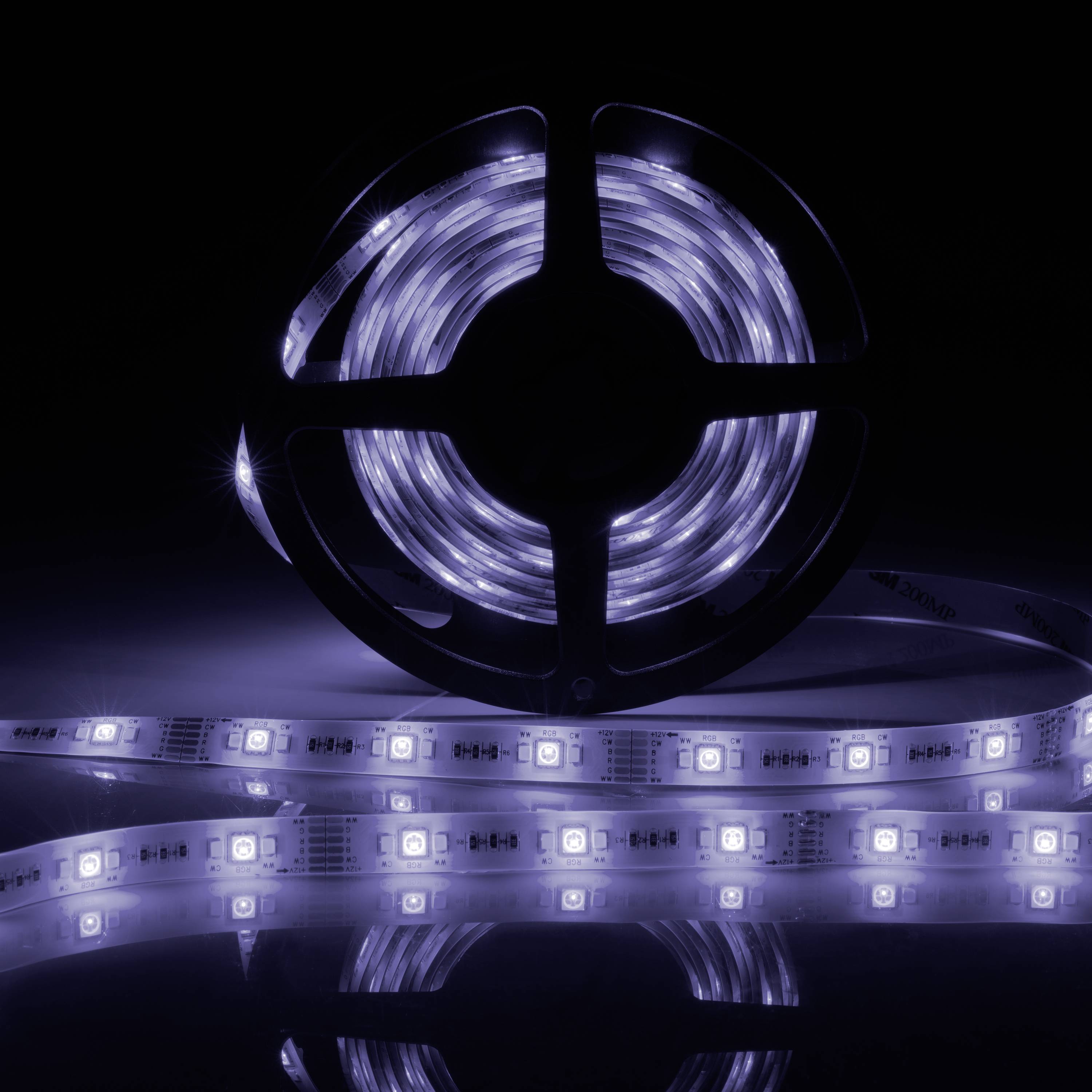 A roll of LED light strip illuminates in a dark room. The strip is partially unrolled, showing several glowing diodes.