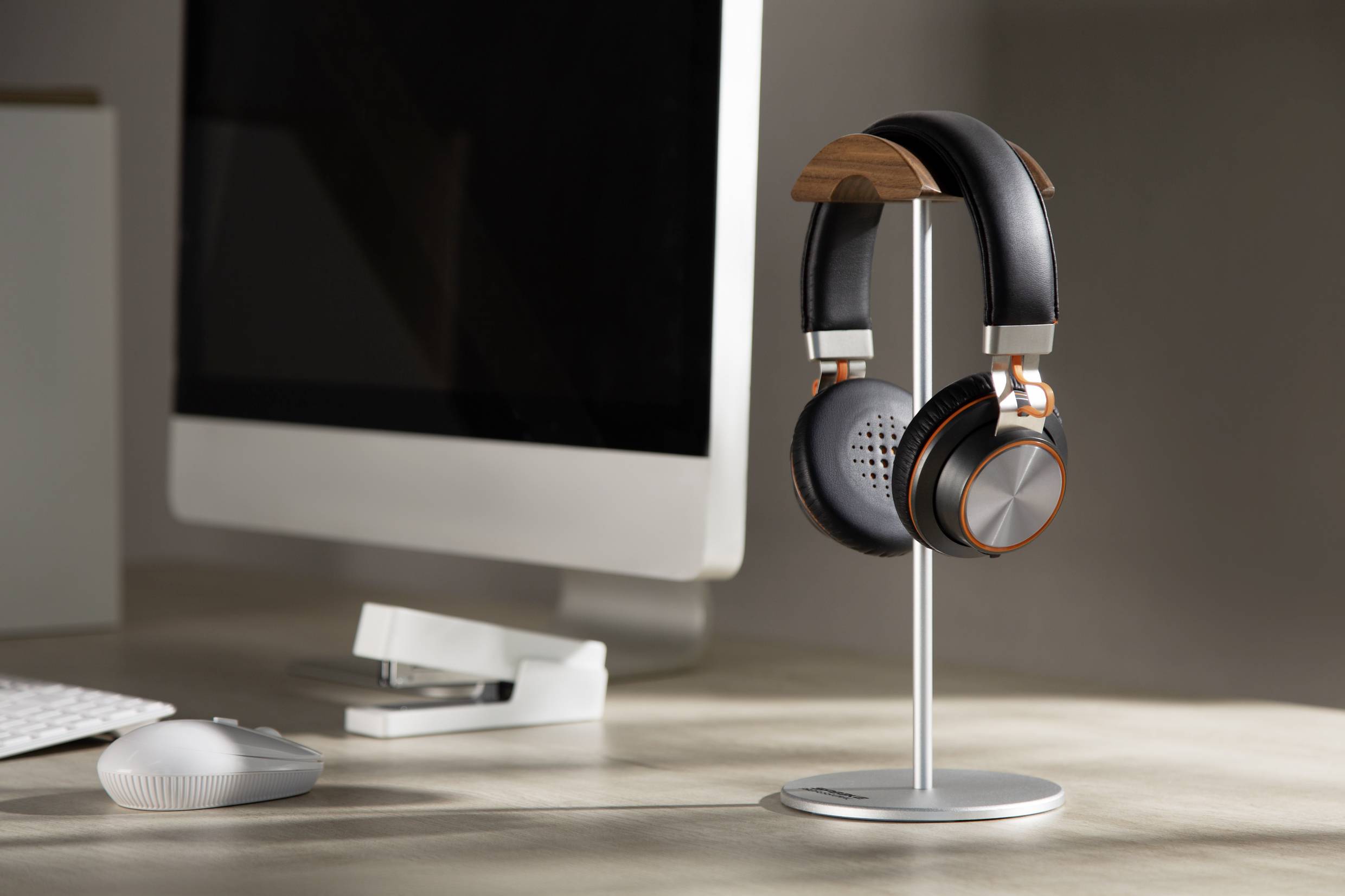 A desk with a computer monitor and headphones on a stand; modern office equipment.<br><br>Note: While the translation is straightforward, I ensured it uses British English spelling and phrasing, maintaining the original meaning and context.