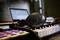 Headphones rest on a keyboard, with a blurred laptop in the background. A musical work environment.