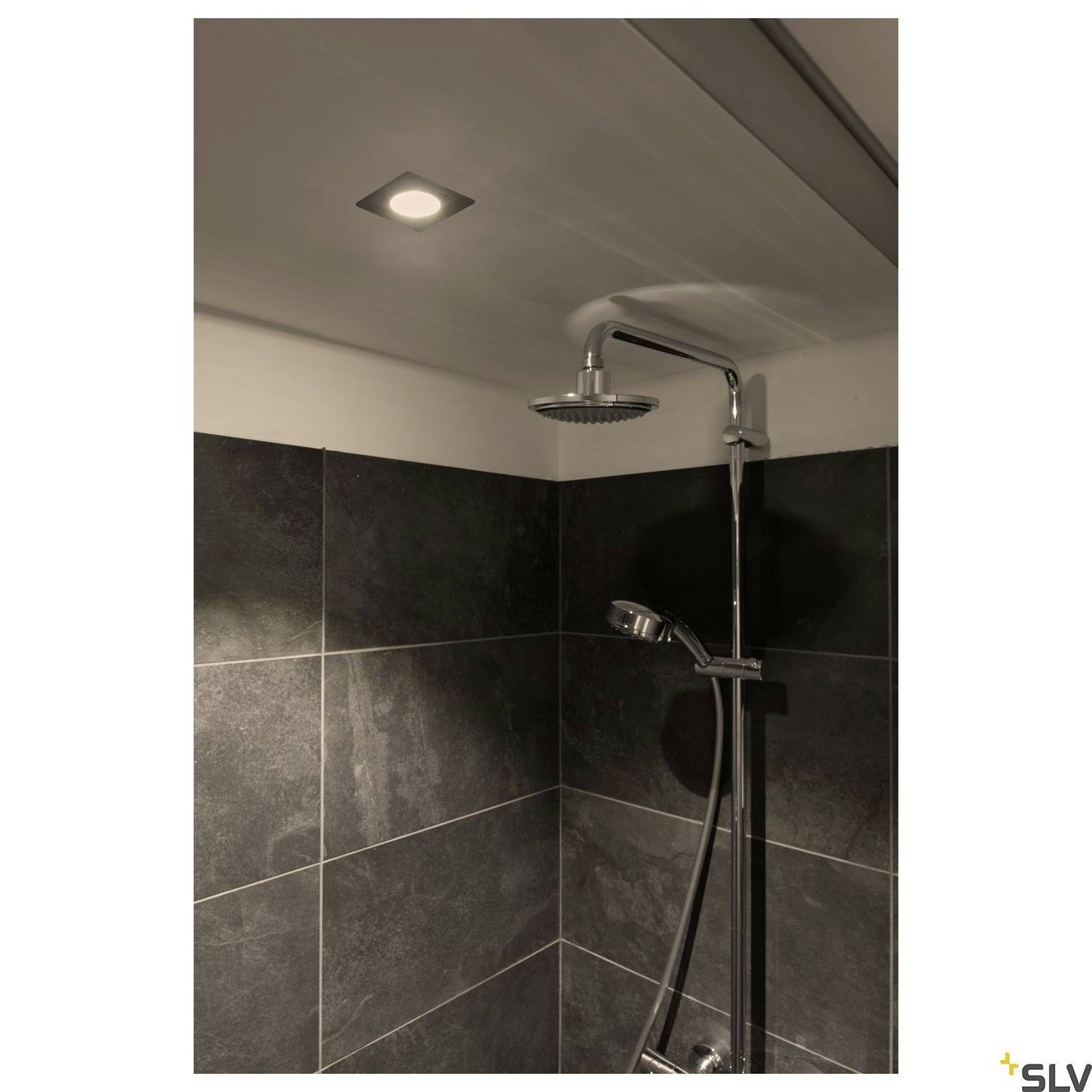 A modern shower with dark tiles, a square shower head and integrated ceiling lighting.