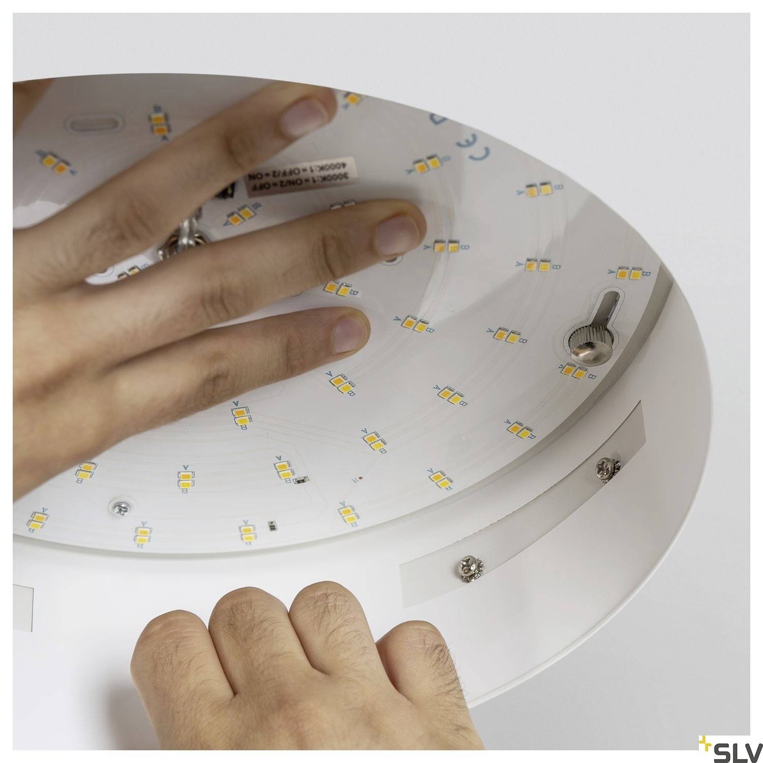 Hand-mounted LED light with visible LED chips and screws in close-up.