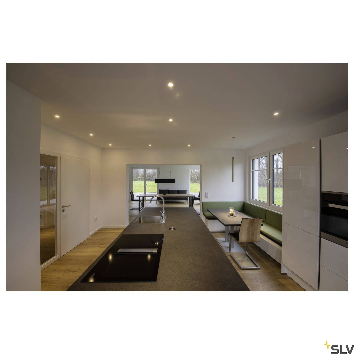 Modern kitchen with a central cooking island, dining table and green windowsill. Bright lighting and large windows allowing plenty of natural daylight.