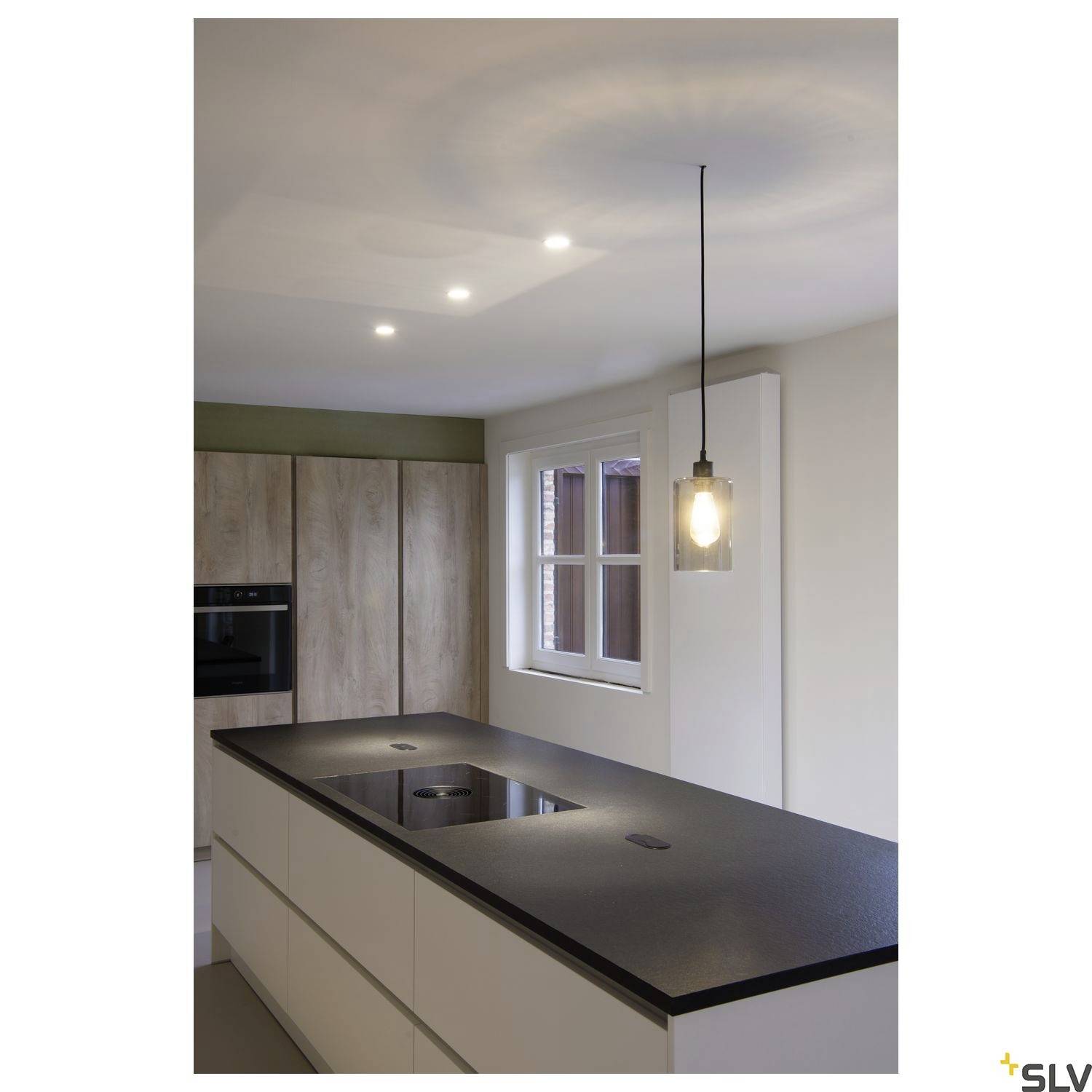Modern kitchen with a central island, induction hob and hanging pendant light. Natural lighting from a window on the right.