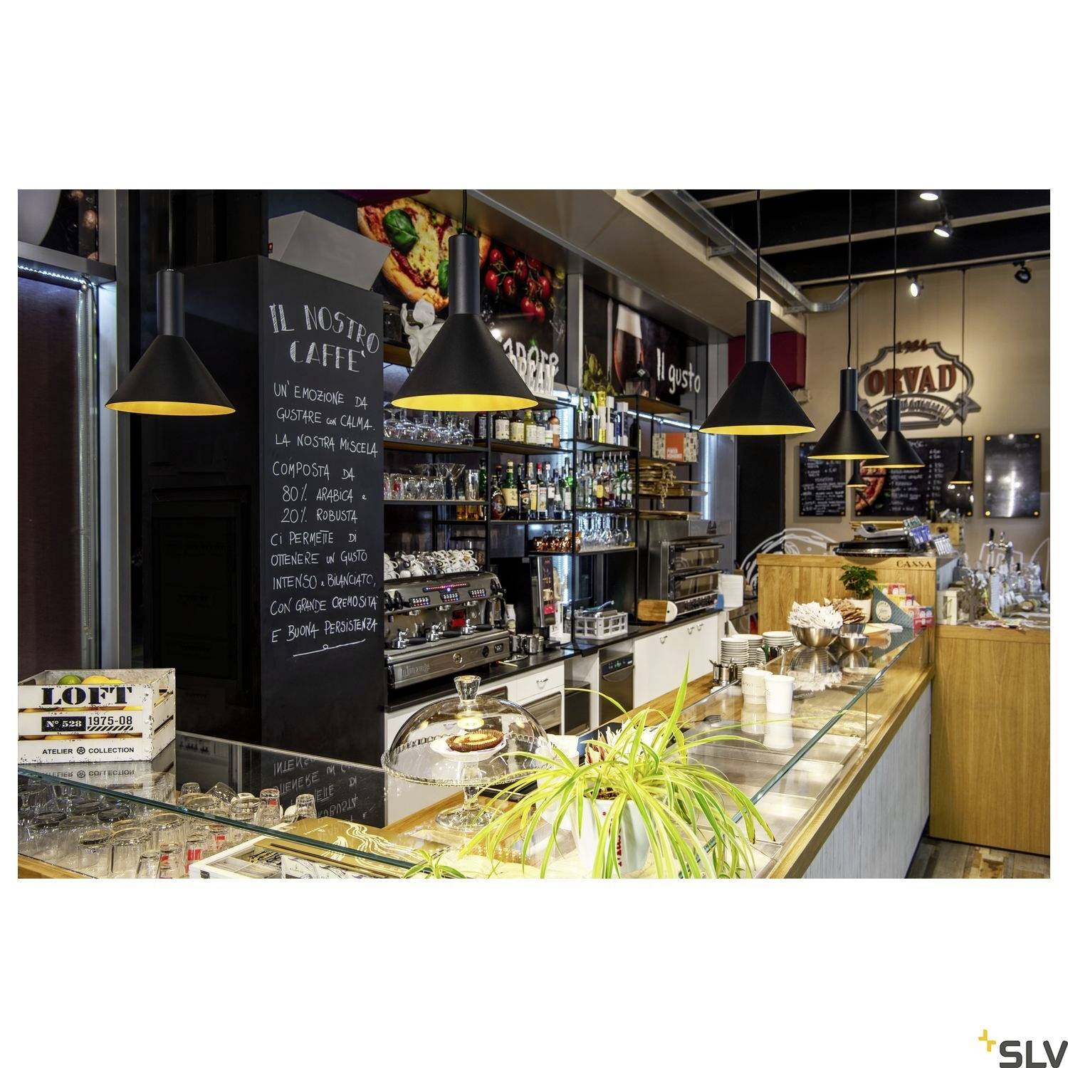 A modern café with a counter, bakery goods, plants, and a menu on the wall. Modern lighting gives the space an inviting atmosphere.
