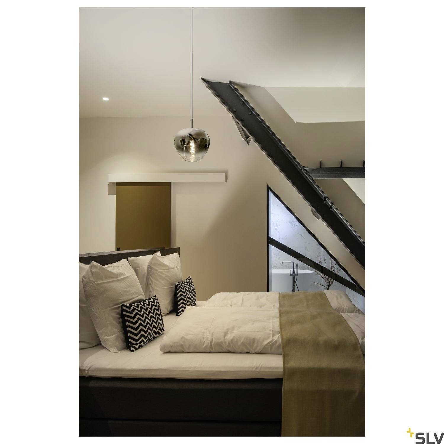 Bedroom with a double bed, decorative cushions, an angled glass window and a modern hanging lamp. Minimalist design.