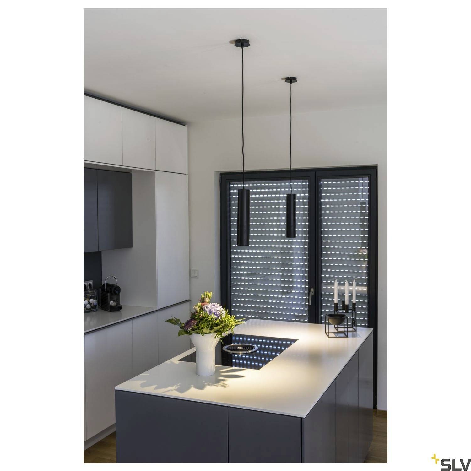 Modern kitchen with an island, two pendant lights, induction hob and window with roller blinds. A flower bouquet and candles on the island.