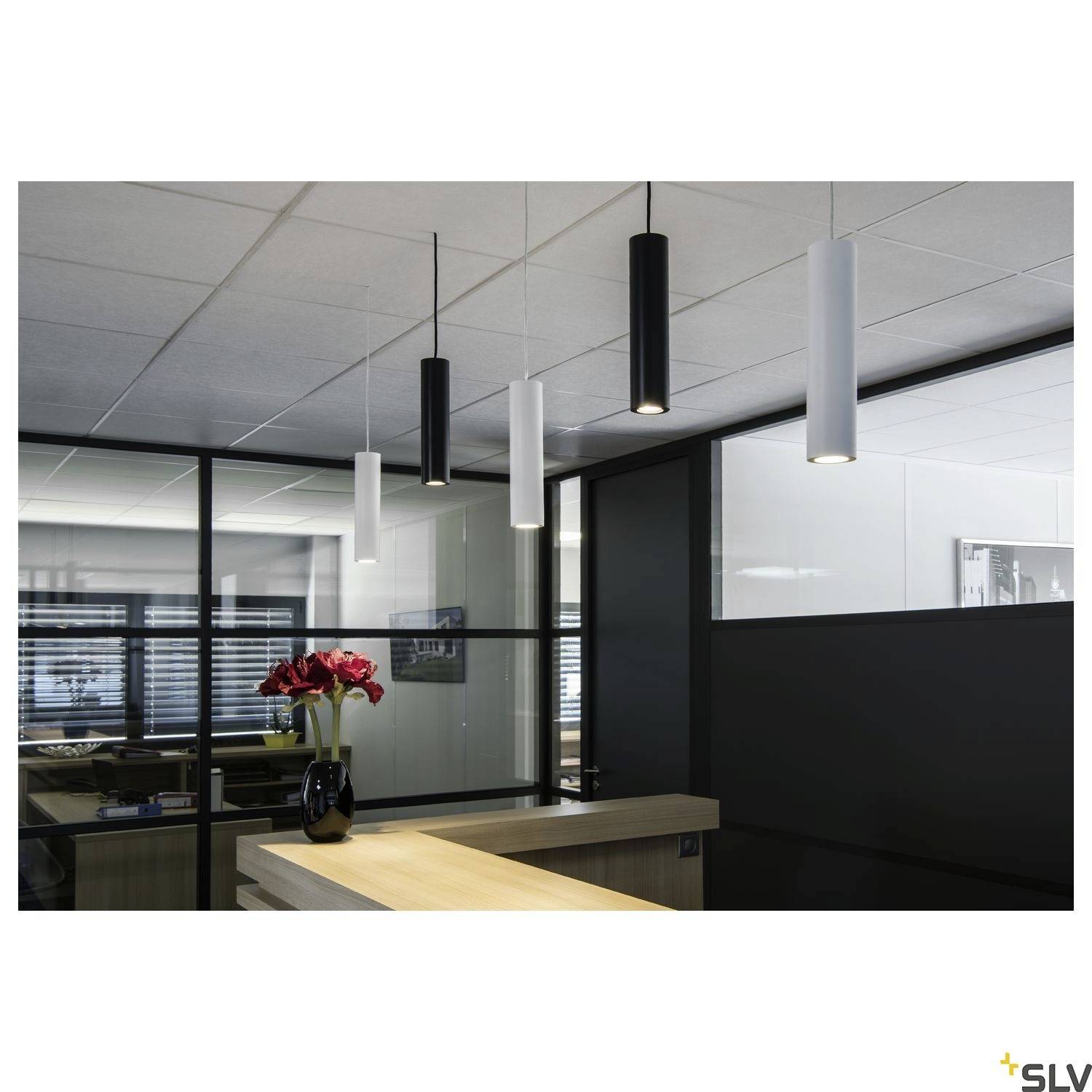 A modern office with a wooden reception desk, featuring a vase with red flowers. Four slender pendant lights hang from the ceiling.