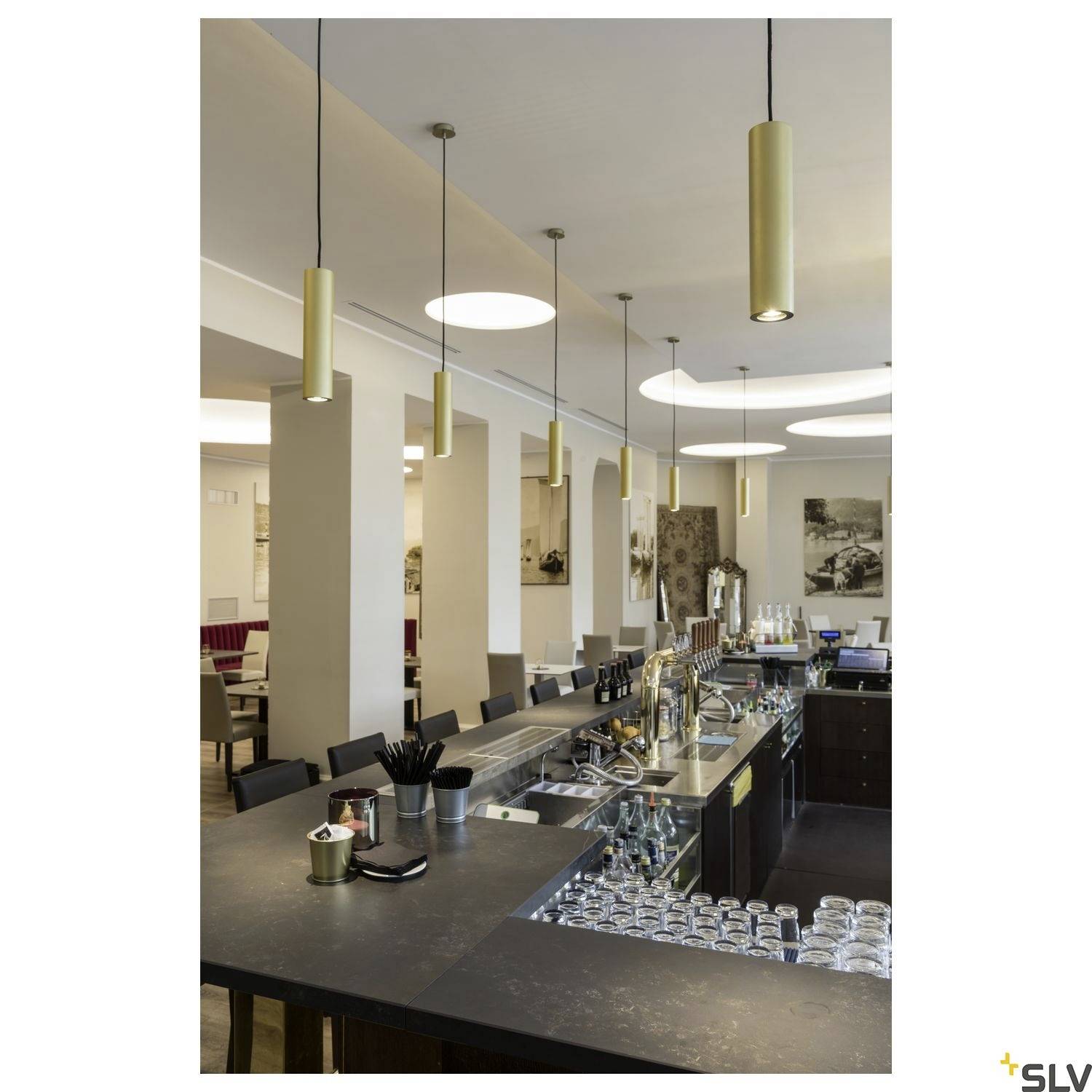 Spacious, modern café interior with a counter, hanging lamps, glasses, and seating areas in the background. Cosy and stylish atmosphere.