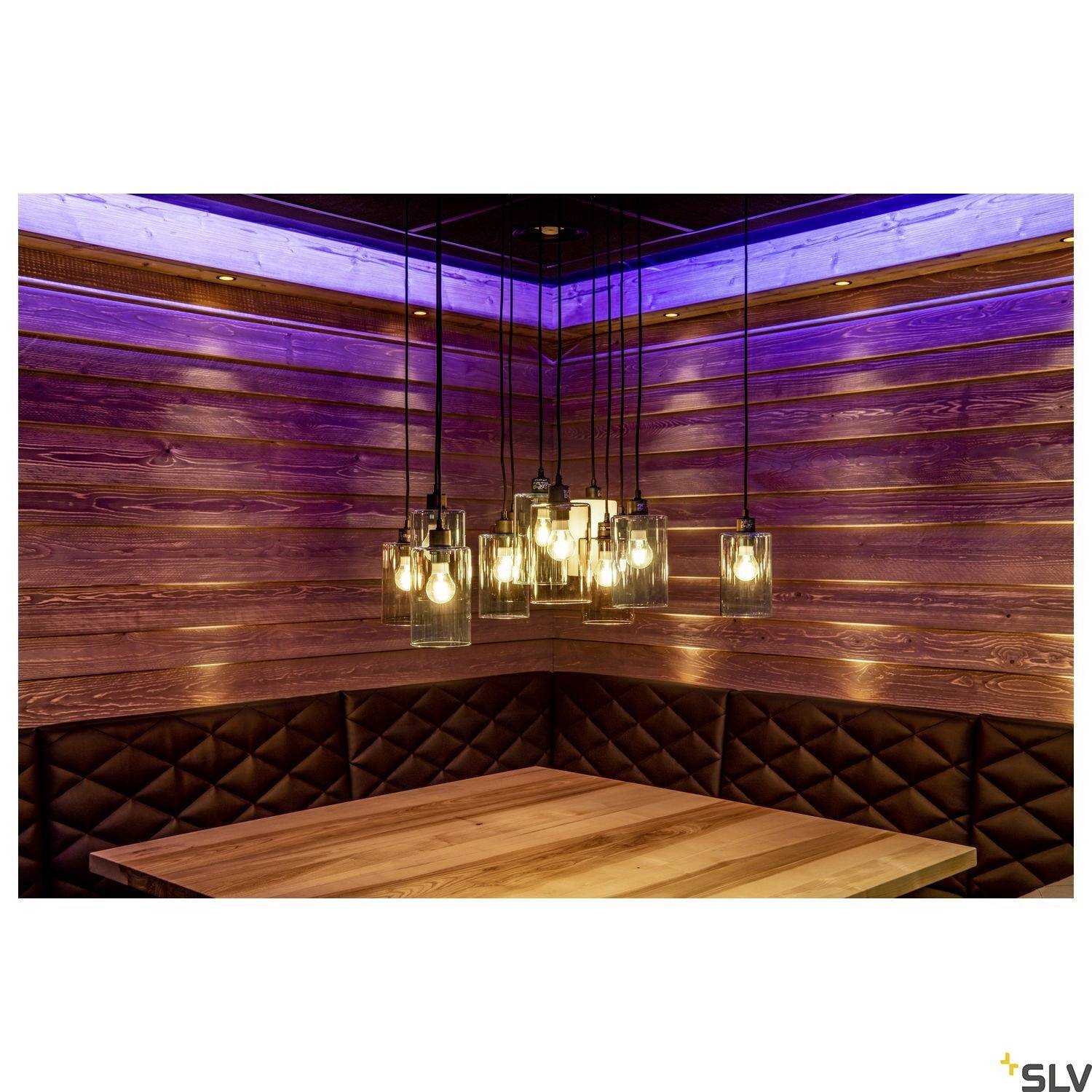 Wooden table in a cosy room with padded wall panelling and pendant lights providing soft, warm illumination.