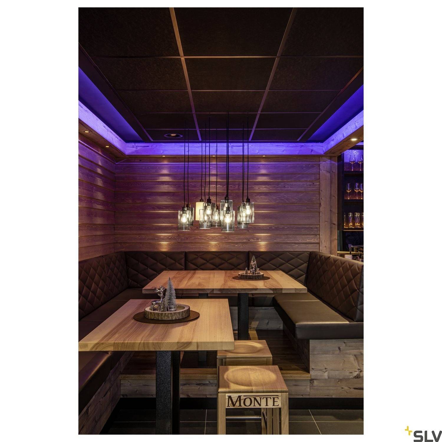 A cosy restaurant with wooden walls and blue ceiling lighting. Two seating alcoves with wooden and faux leather furnishings, illuminated by hanging glass light fixtures.