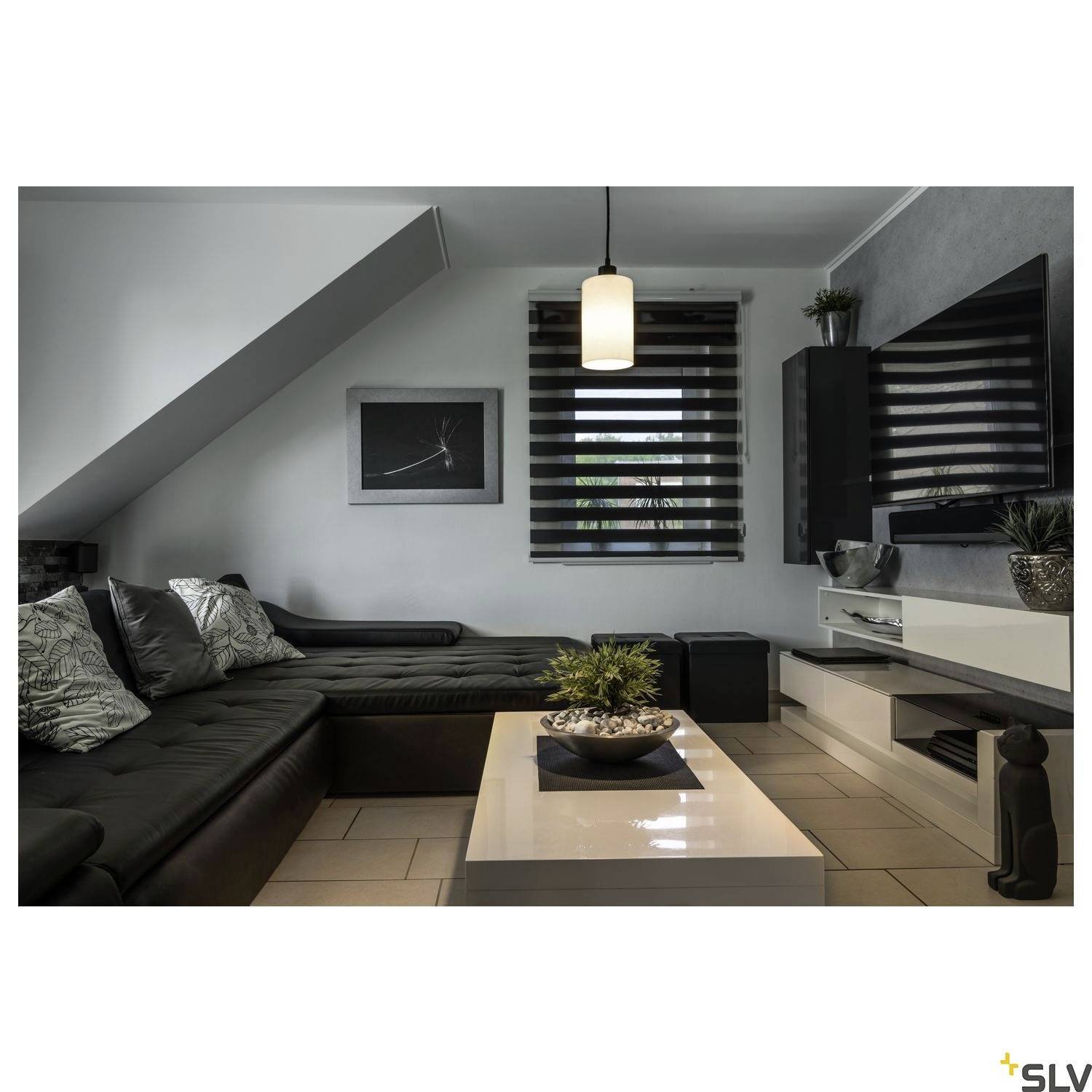 A modern furnished living room with a black sofa, coffee table and decorative plants in a minimalist style.