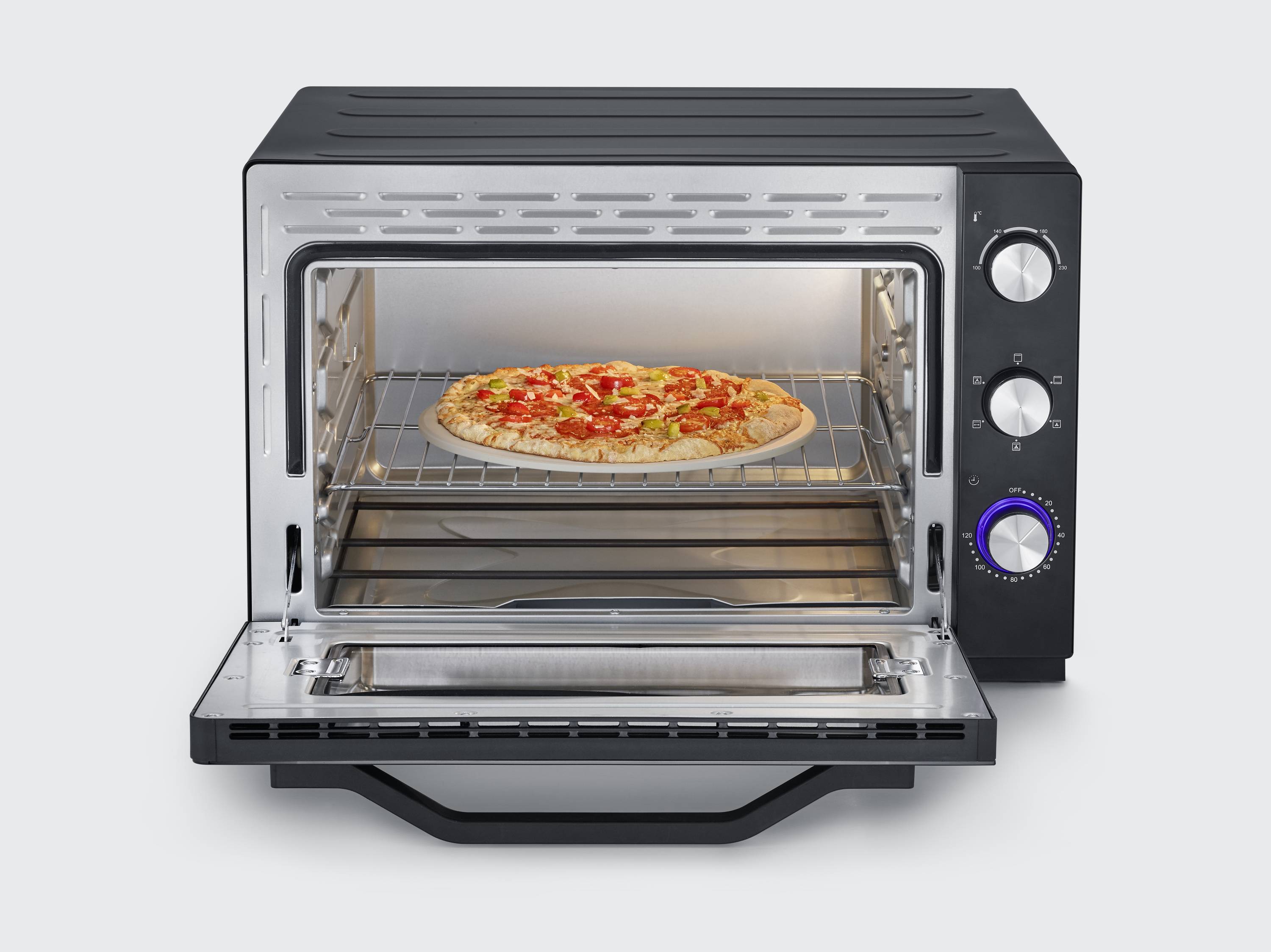 An open mini oven with a baked pizza on the rack. The oven has rotary knobs for setting temperature and time.