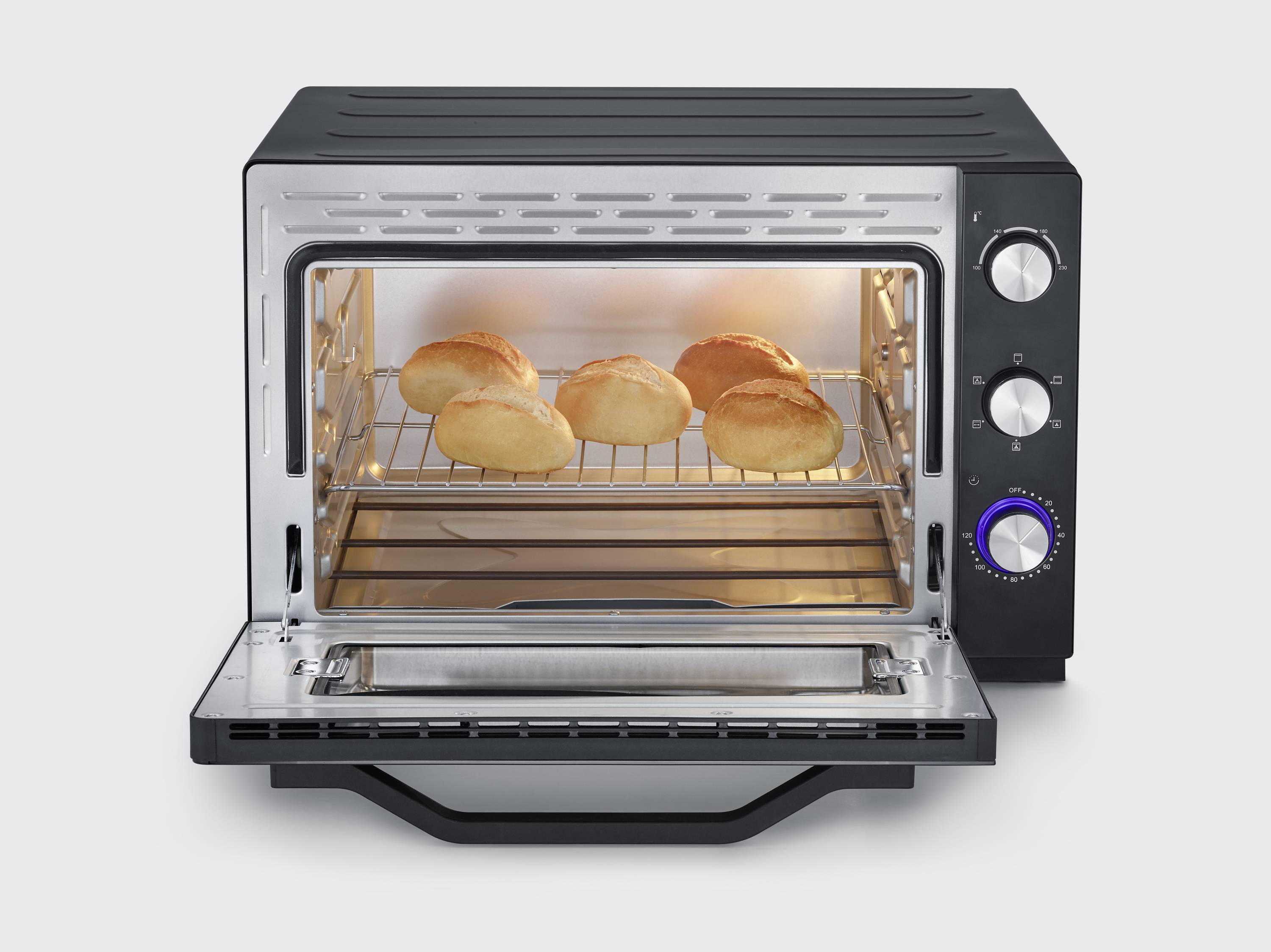 A toaster oven with an open door, displaying five golden-brown rolls on the rack, enclosed within a sleek, black casing with rotary controls.