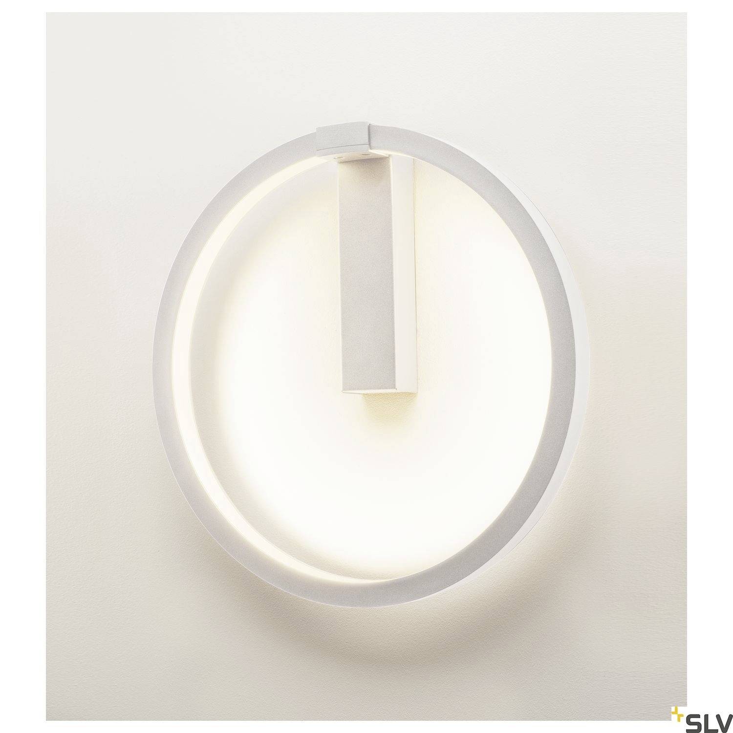 A round, modern wall light in white with an illuminated outer edge, centrally mounted vertical element.
