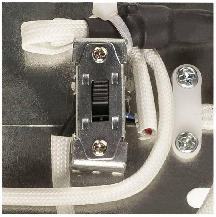 Close-up of a toggle switch in an electrical device with surrounding cables and screws.