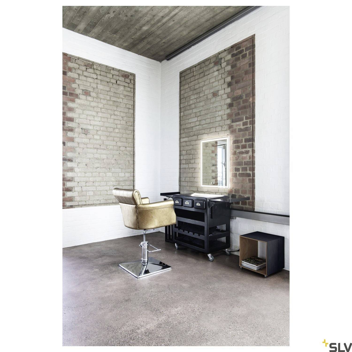 A hairdressing chair sits in a stylish salon with exposed brick walls and an industrial design.