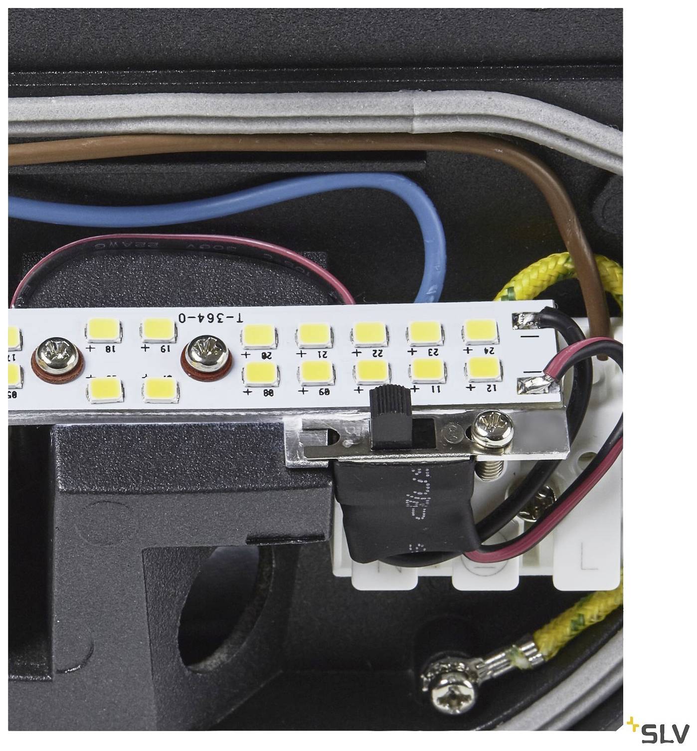 Close-up of an electronic component with LED light bar, cables, and connectors. Manufacturer's marking visible in the bottom right.
