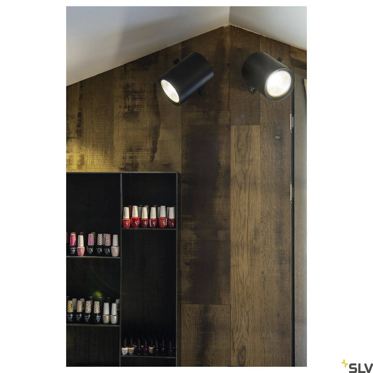Spotlights illuminate a wall with a wood-effect finish. A shelf holds various nail polish colours.