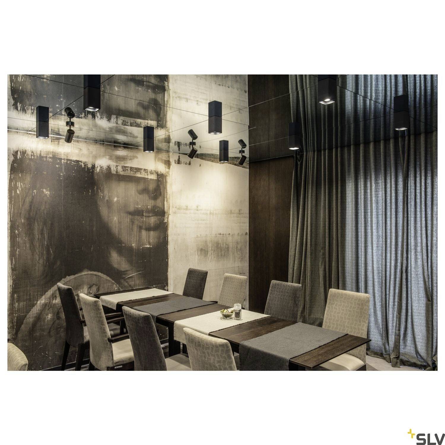 A stylishly appointed dining area with multiple tables and chairs, decorated with contemporary pendant lights and wall art.