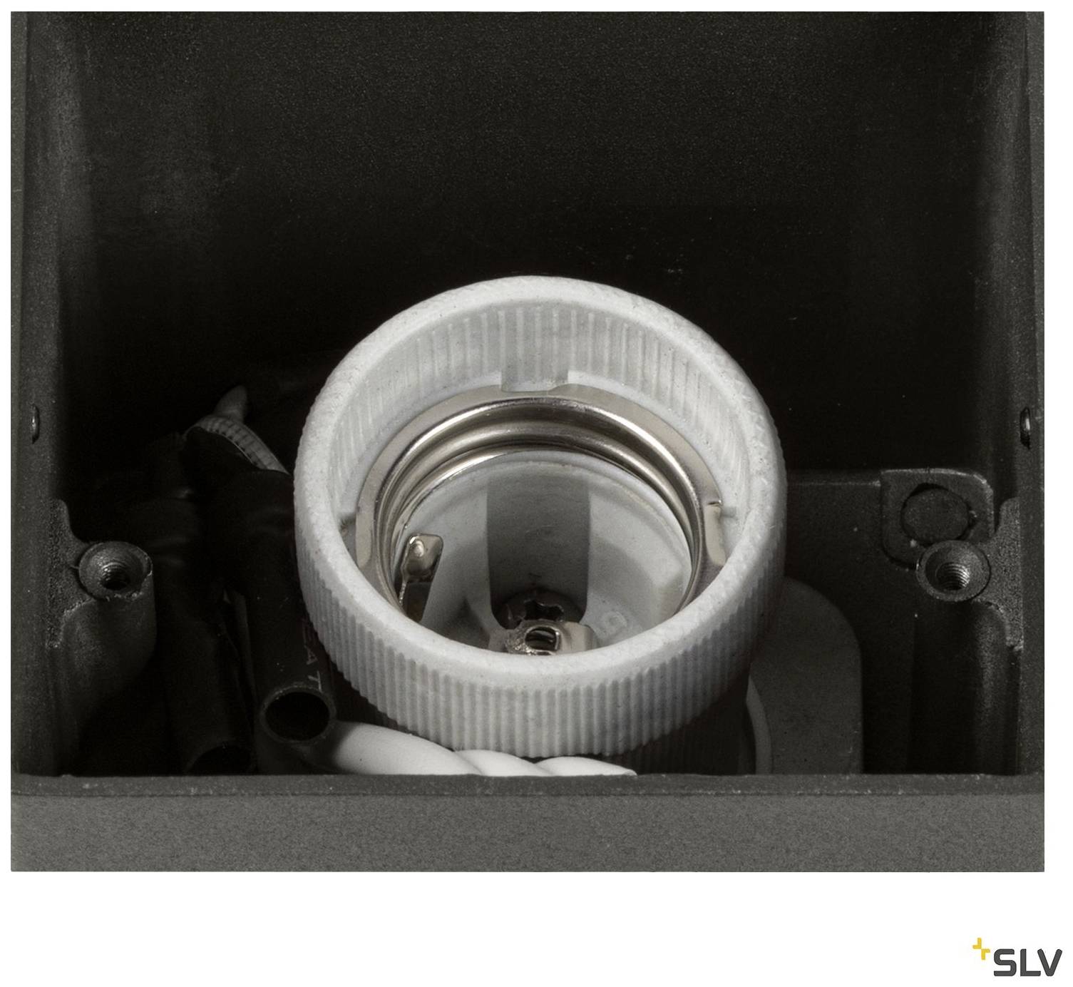 Close-up of a metal and plastic lamp socket, installed in a square housing. Cables are partially visible in the background.