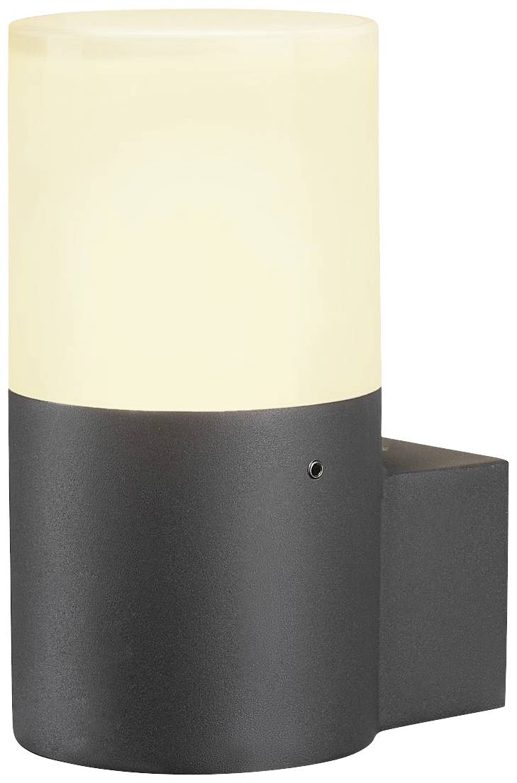 A black wall light with a cylindrical, matte lampshade, which emits warm light, is mounted on a white wall.