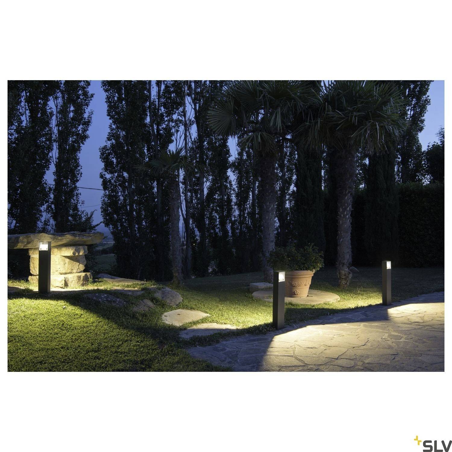 Path lighting with four illuminated bollard lights in a garden landscape, surrounded by tall trees at dusk.
