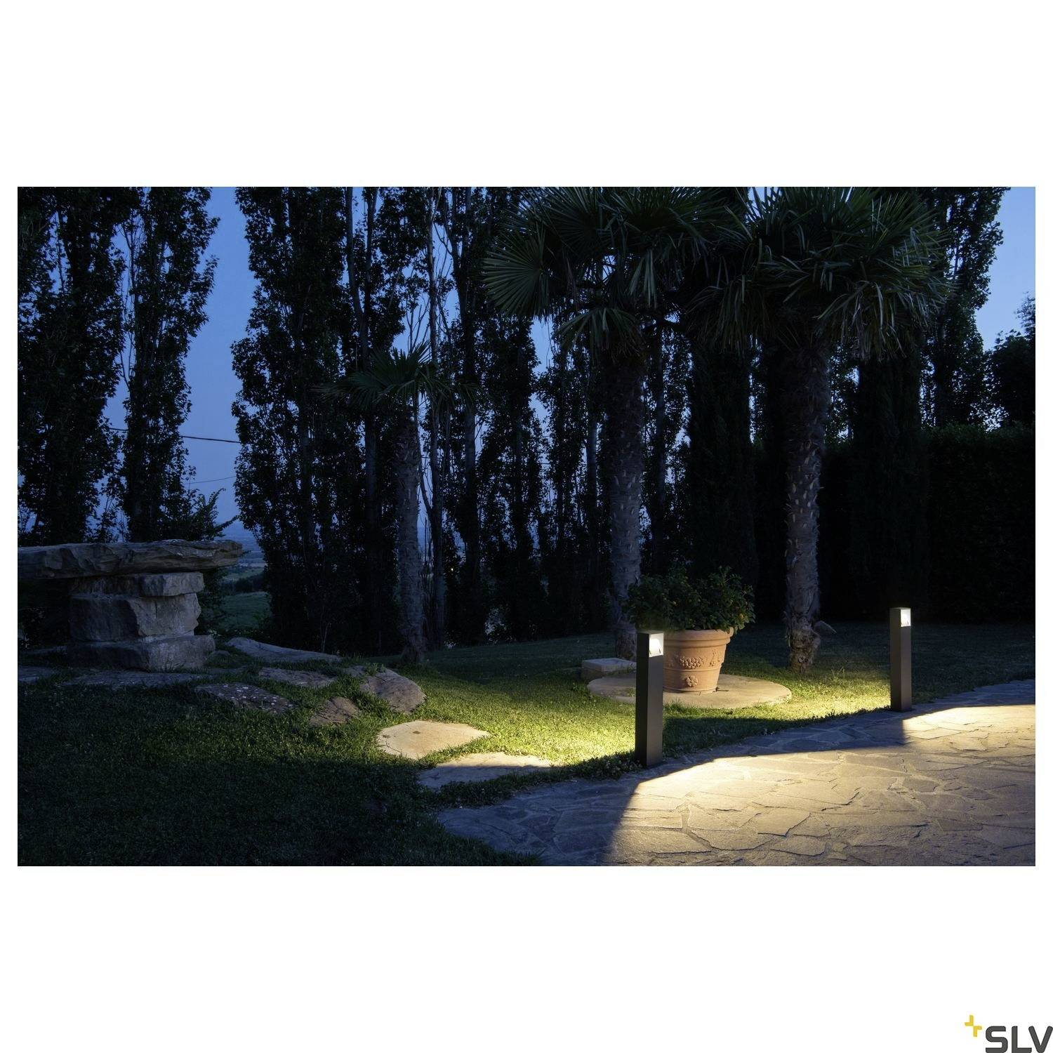 Garden at night with an illuminated path; three bollard lights illuminate the path between tall trees and a lawn area.